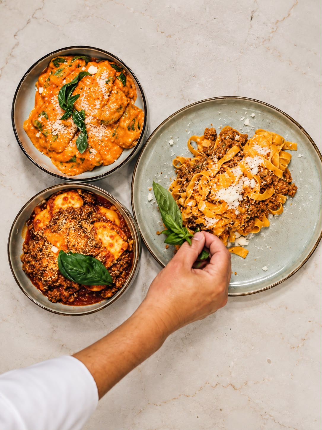 Tres platos de pasta recién preparada con albahaca y queso